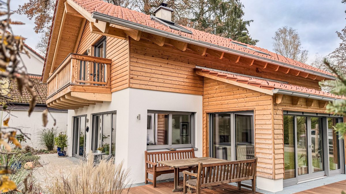 Einfamilienhaus München mit Wintergarten und Balkon. Erdgeschoss verputzt. Obergeschoss mit Holzschalung