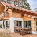 Einfamilienhaus München mit Wintergarten und Balkon. Erdgeschoss verputzt. Obergeschoss mit Holzschalung