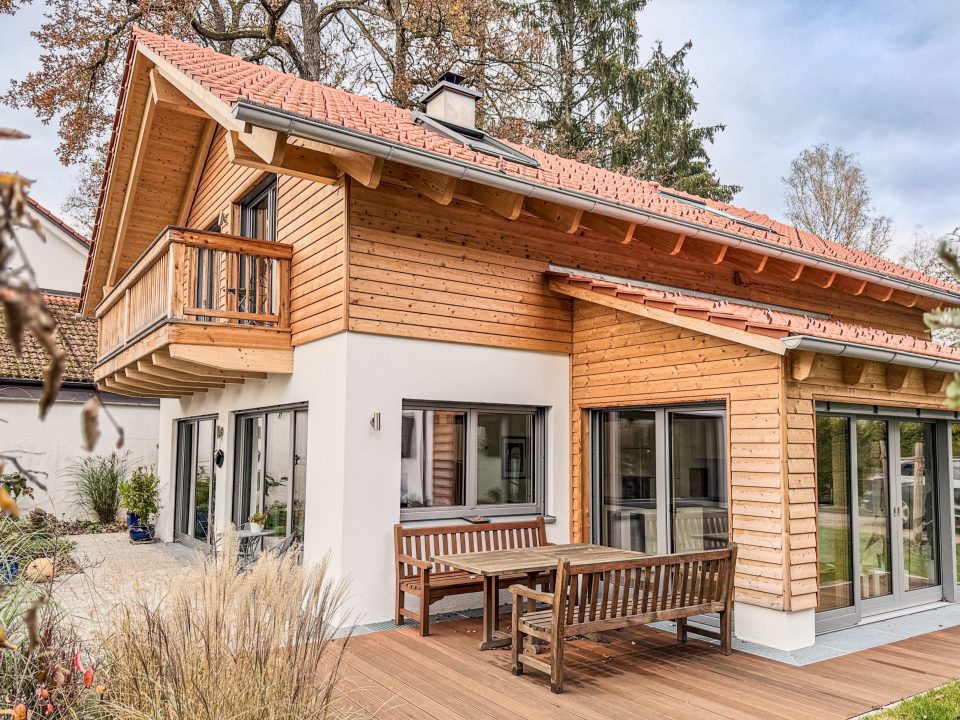 Einfamilienhaus München mit Wintergarten und Balkon. Erdgeschoss verputzt. Obergeschoss mit Holzschalung