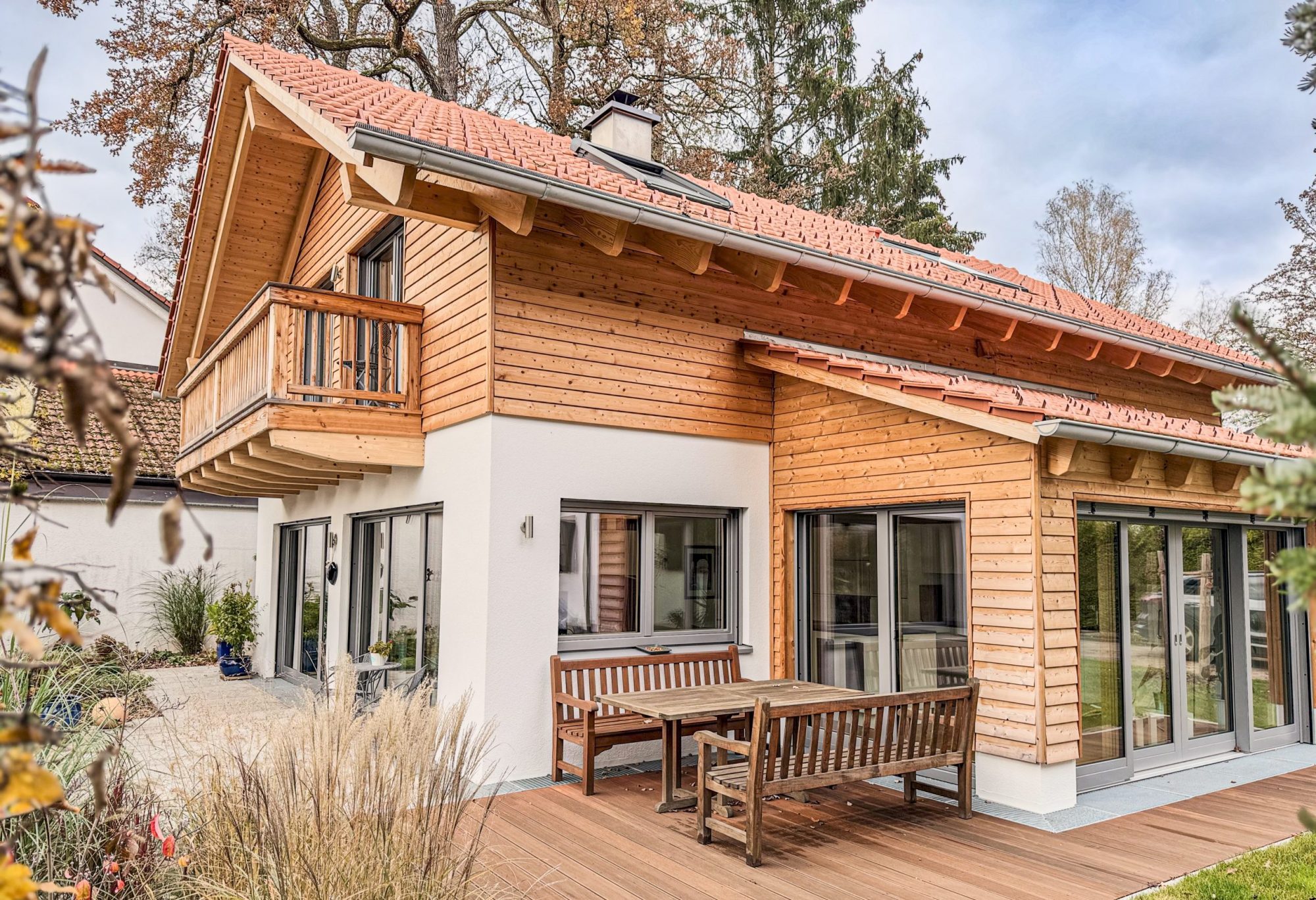 Einfamilienhaus München mit Wintergarten und Balkon. Erdgeschoss verputzt. Obergeschoss mit Holzschalung