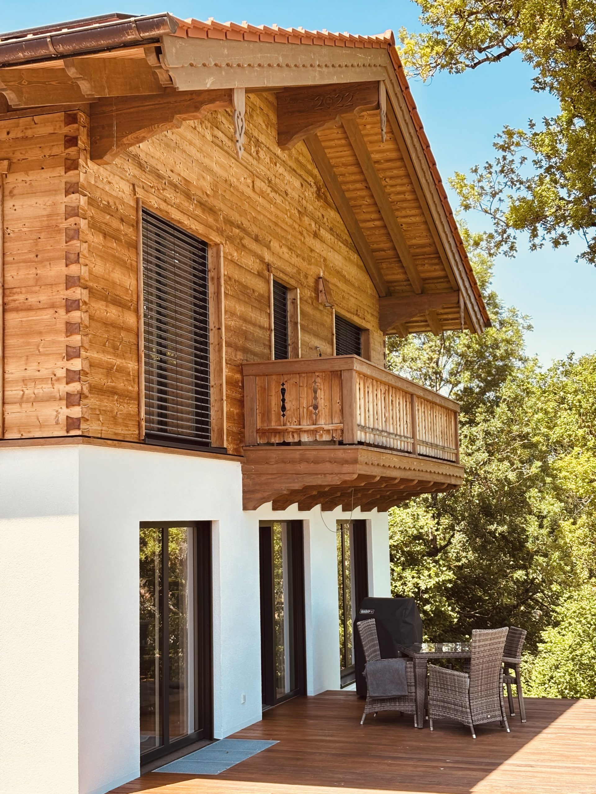 Holzhaus in Hausham, Einfamilienhaus bayerisch, traditionell, mit bodentiefen Fensterelementen. Gehackte Holzschalung mit Tiroler Eckplatt Verbindung.